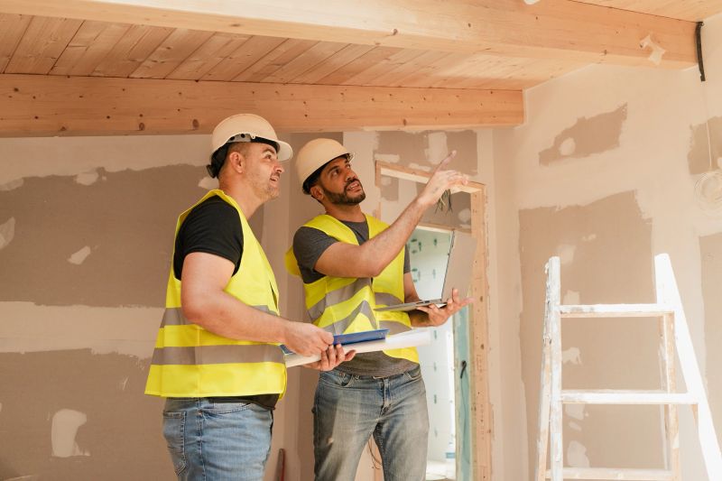 Two Construction worker and architect discussing renovation house project using laptop and blueprint