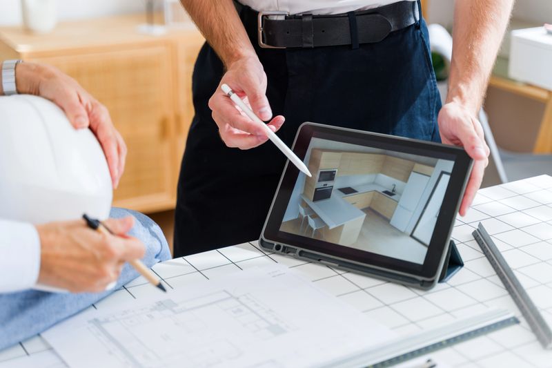 Two architects discussing kitchen interior design shown on a digital tablet