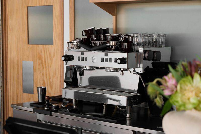 A stylish and modern coffee machine sits proudly on the countertop, surrounded by elegant glasses and colorful flowers