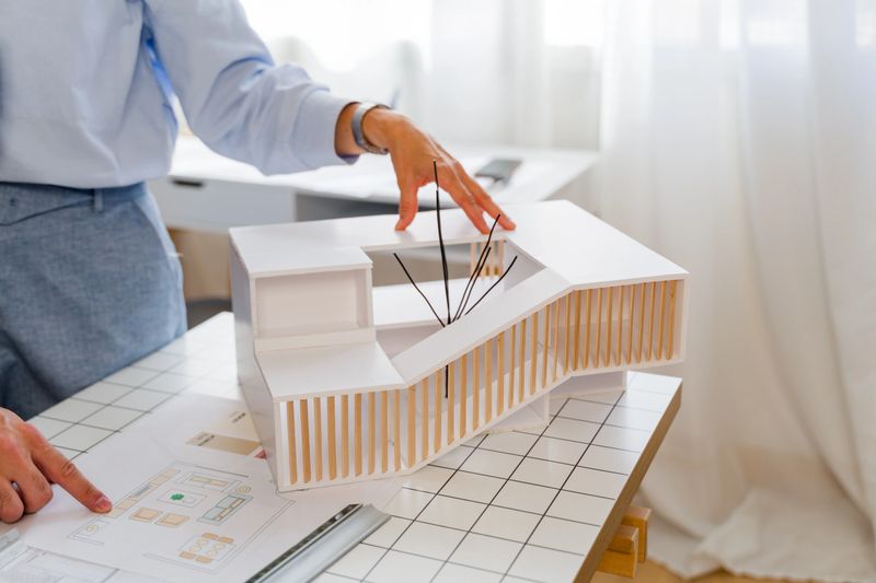 Architect examining an architectural model and blueprints at a desk