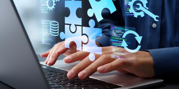 Hands typing on laptop with floating puzzle and code icons.