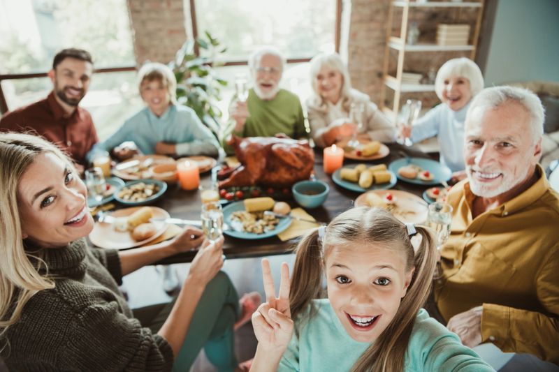 A joyful multi generational family gathers around a festive table enjoying a Thanksgiving style meal with turkey bread rolls and candles; everyone smiles and toasts creating warm memories.