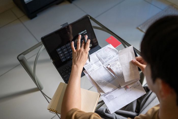 Person managing finances with receipts and a tablet calculator.