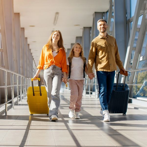 Family walking with luggage through an airport terminal.