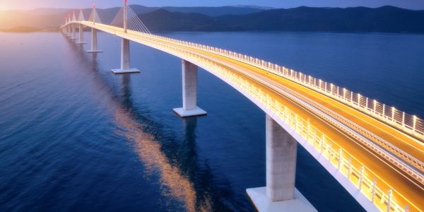 A lit bridge over water at dusk.
