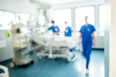 Blurred hospital room with medical staff and patient bed.