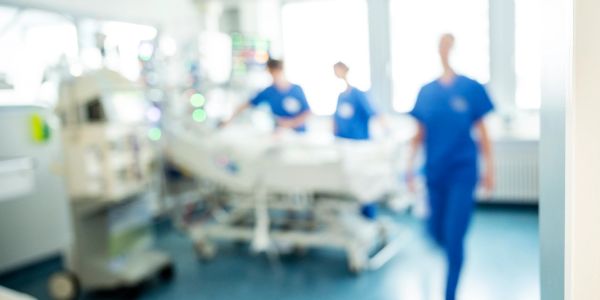 Blurred hospital scene with medical staff and equipment.