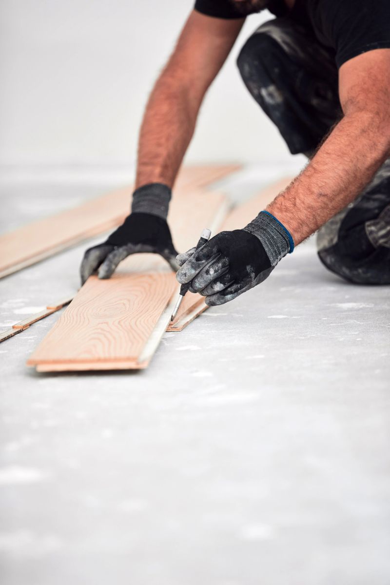 Professional handyman installing laminate flooring in a new apartment.