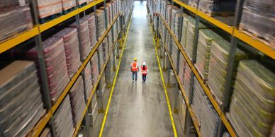 Two workers walking down a large warehouse aisle.