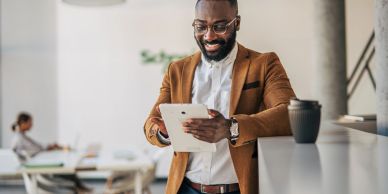 Man smiling while using a tablet in an office.