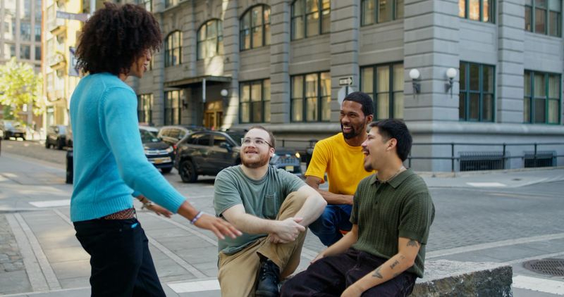 A diverse group of four best friends hanging out on a sidewalk in DUMBO, Brooklyn, New York City.