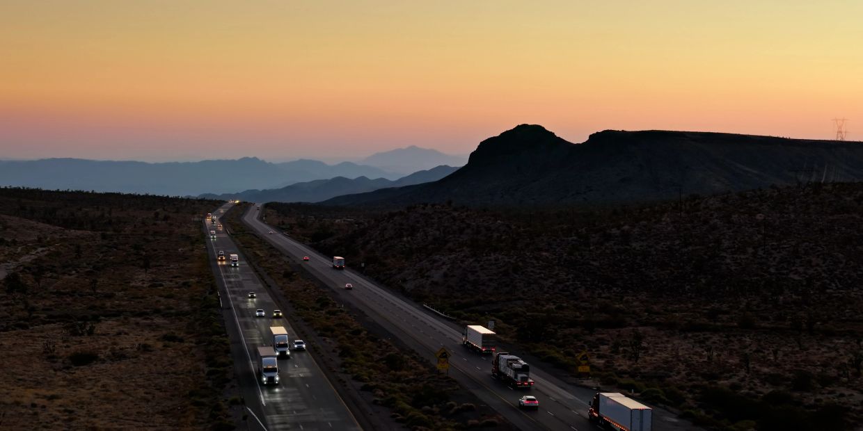 Sunset over a highway with trucks and cars driving.
