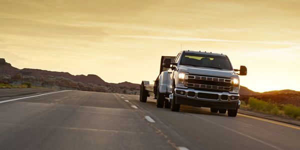 Pickup truck driving on a highway during sunset.