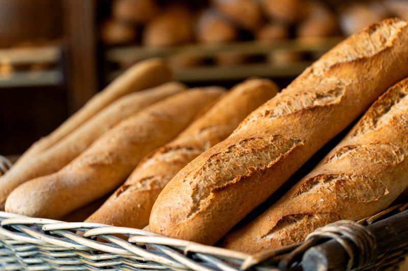 Golden crusty baguettes piled in a rustic wicker market basket, warm artisan french bread ready for sale in a bakery display