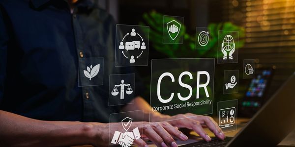 Person typing on laptop with CSR icons representing corporate social responsibility.