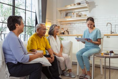 A nurse engaging with three elderly people in a cozy living room setting.