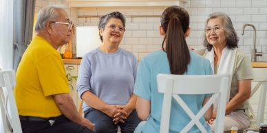 Senior adults talking with a nurse in a cozy kitchen.