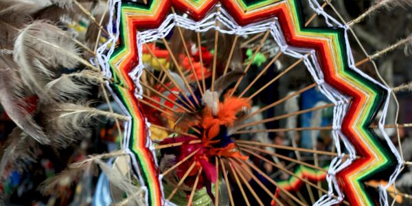 Colorful traditional woven mandala with feathers.