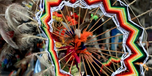 Colorful traditional woven mandala with feathers.
