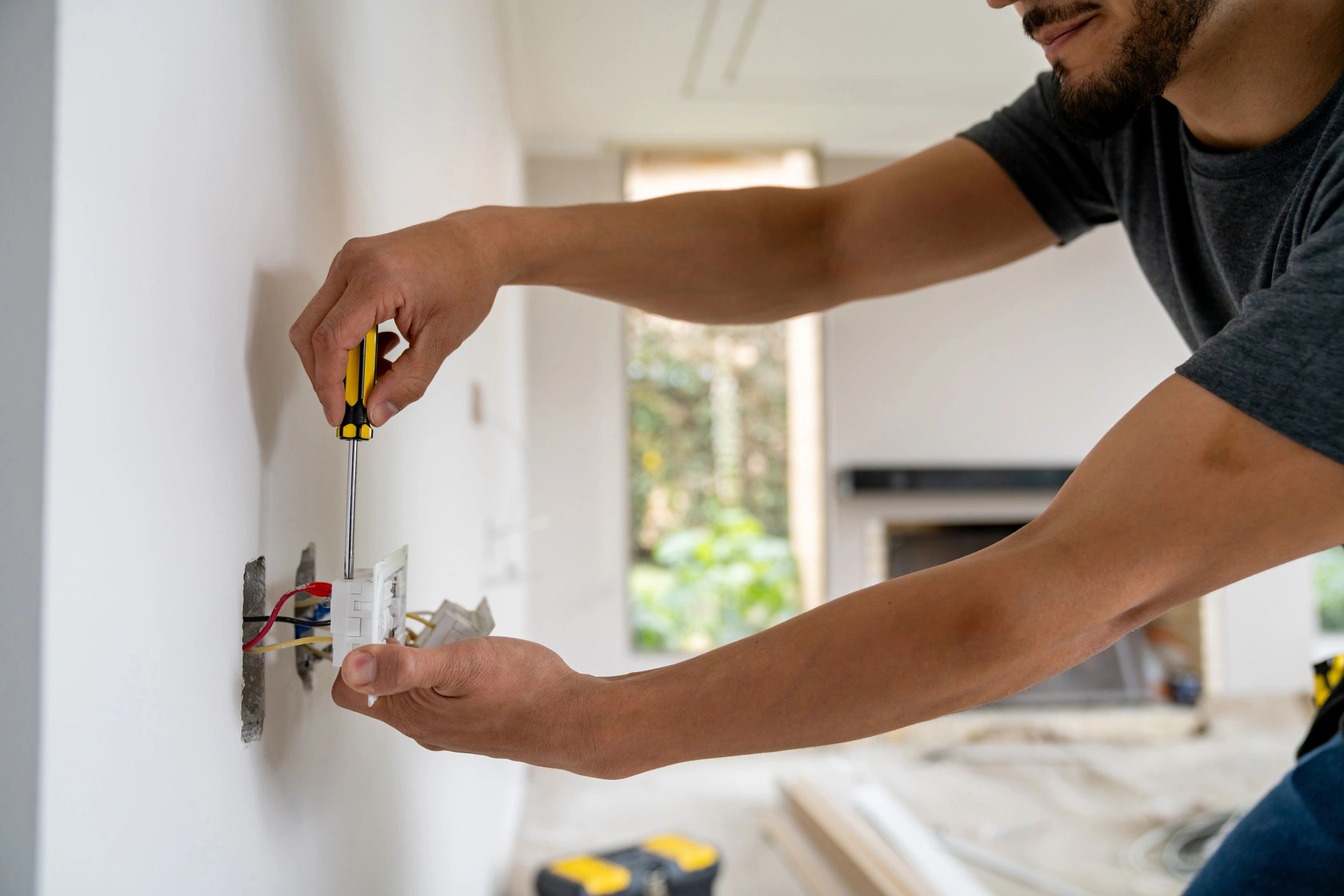 Man fixing electrical outlet with screwdriver.