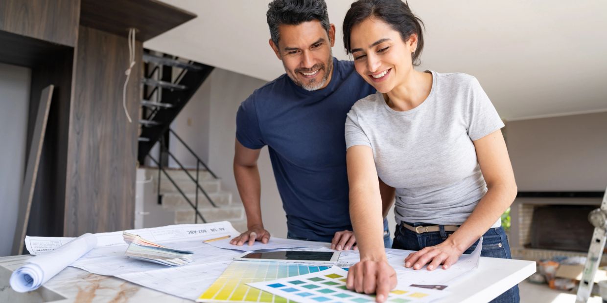 Couple reviewing color swatches and blueprints for home design.