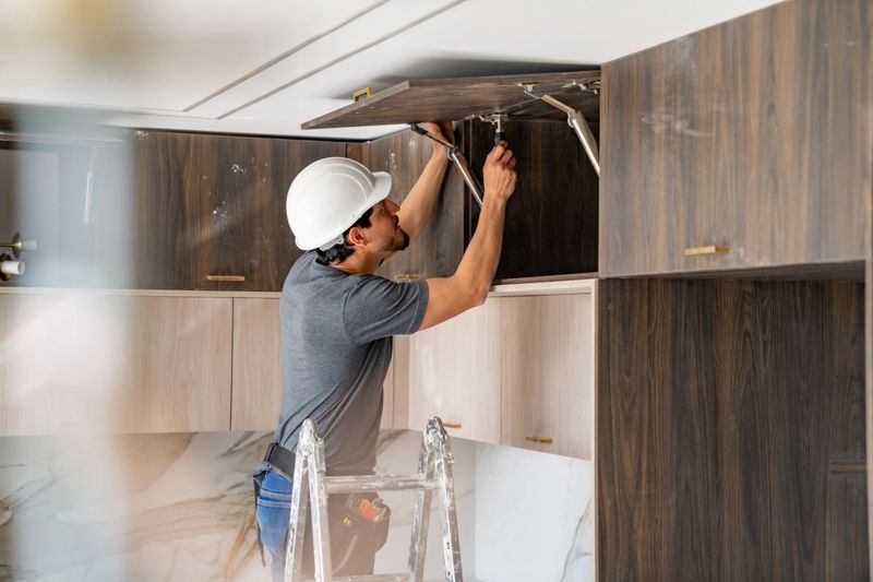 Latin American building contractor installing a cabinet in the kitchen while remodeling a house