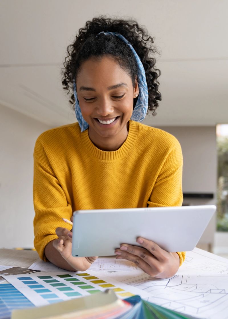 Happy African American interior designer remodeling a house and smiling while using a digital tablet