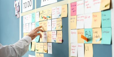 Person managing tasks on a colorful sticky note board labeled TO DO and WORK.