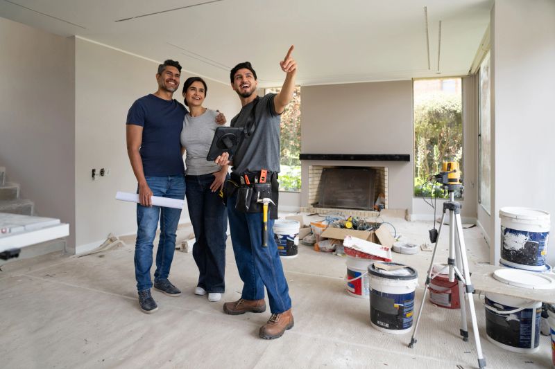 Happy Latin American building contractor pointing away and sharing ideas with a couple while remodeling their house