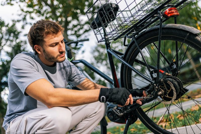 Young man fixes bicycle chain, concept of bike maintenance, repair, cycling, outdoor activity, urban mobility, healthy lifestyle, cycling mechanic.