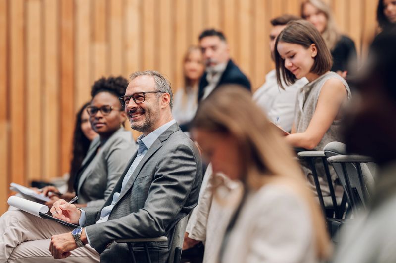 Diverse group of business people listening and taking notes during a corporate conference or educational seminar