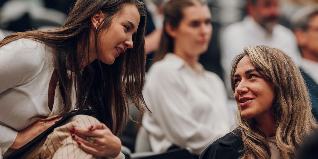 Two women engaged in a friendly conversation at an event.
