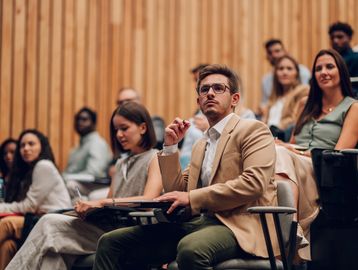 Man attentively listens in a lecture hall among peers.