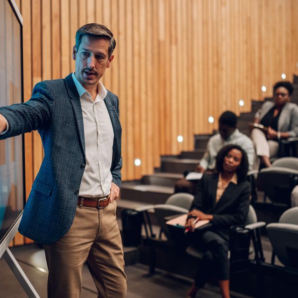 Businessman presenting in a modern conference room with attentive audience.
