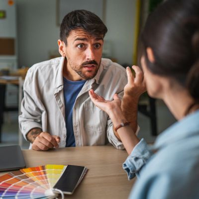 Two people engaged in a serious discussion with color swatches on the table.