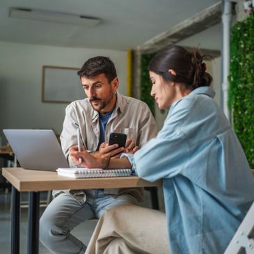 Two colleagues collaborating on a project using a laptop and smartphone.