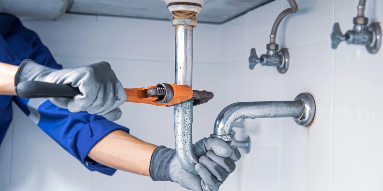 Plumber fixing a pipe under a sink.