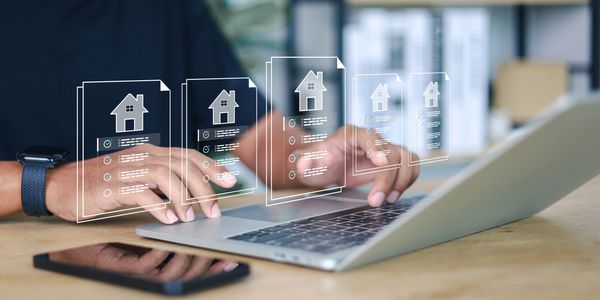 Person using laptop with holographic house icons.