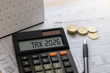 Calculadora con texto 'TAX 2026', monedas y calendario.