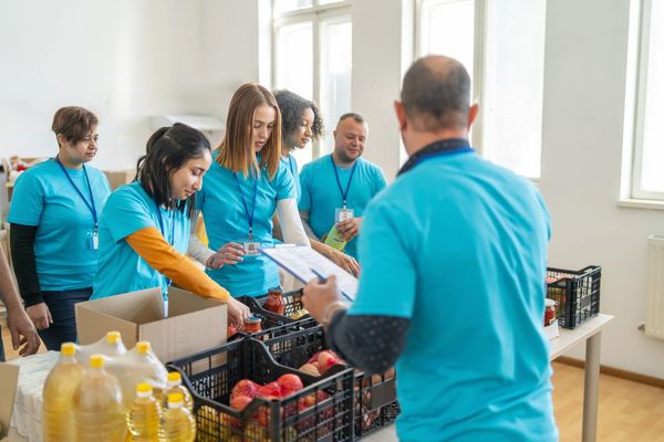 Volunteers in blue shirts sorting food donations indoors.