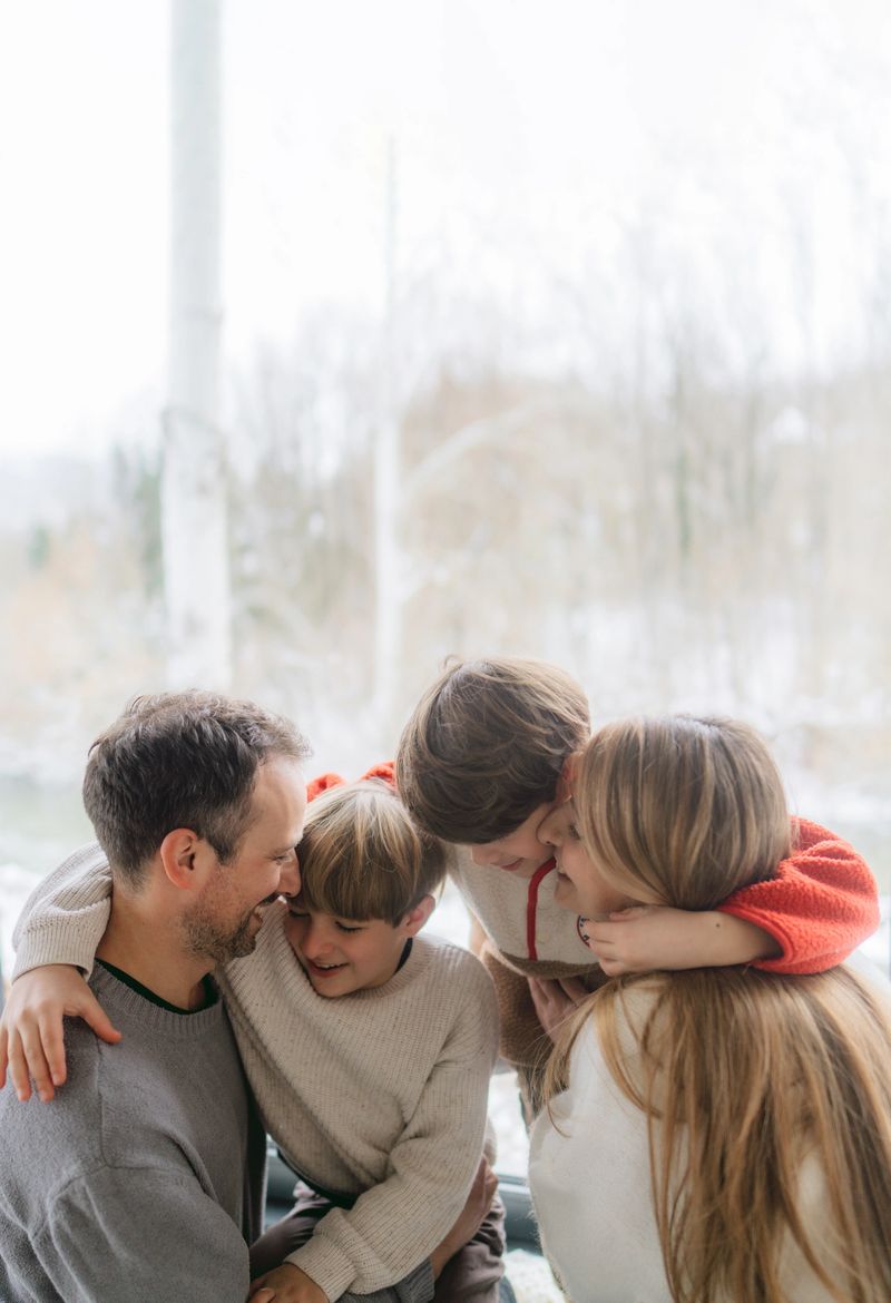 Photo of a cheerful young family, sitting in their cosy home and enjoying each others company while it is snowing outdoors