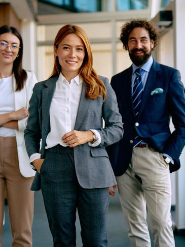 Three confident professionals posing in a modern office environment.