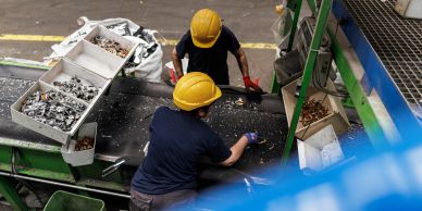 Workers sorting metal scraps on a conveyor belt.