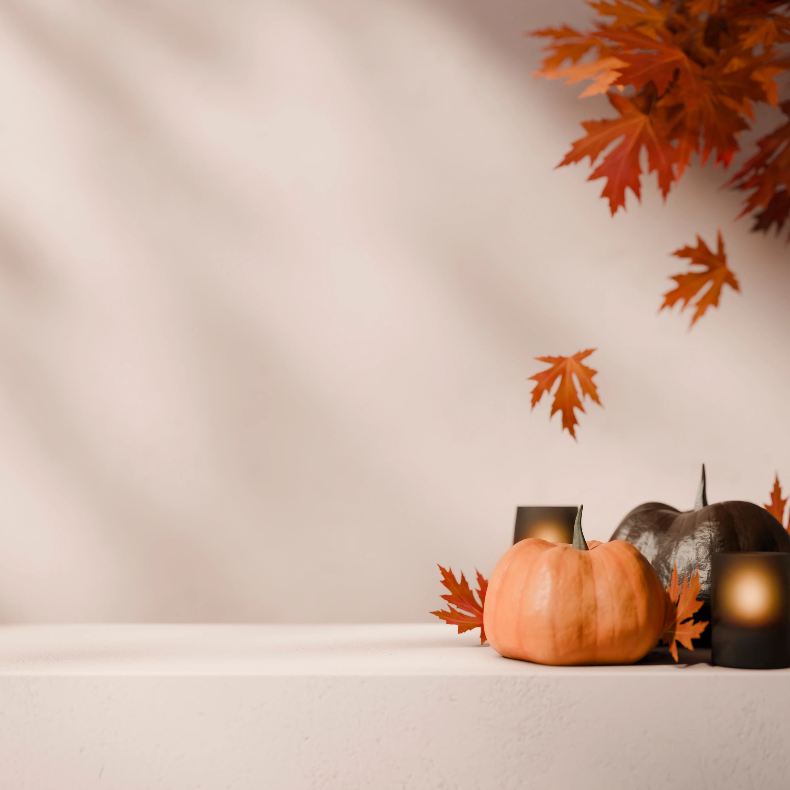 Autumn decor with pumpkins, candles, and orange leaves on a white surface.