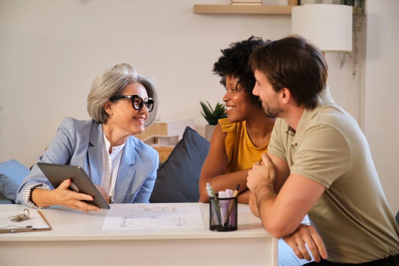 Real estate agent showing tablet to young couple during home consultation