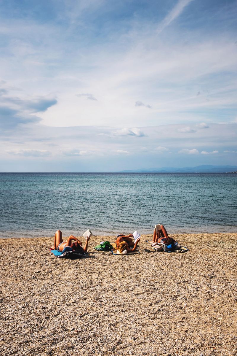 Three female friends reading a book on the beach