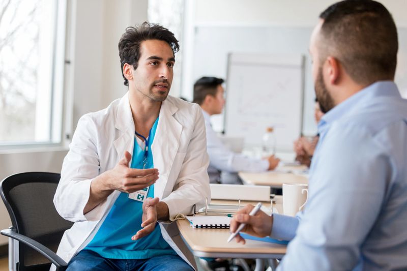 Healthcare professional explaining concepts to a patient during a meeting, emphasizing teamwork and communication in a professional setting.