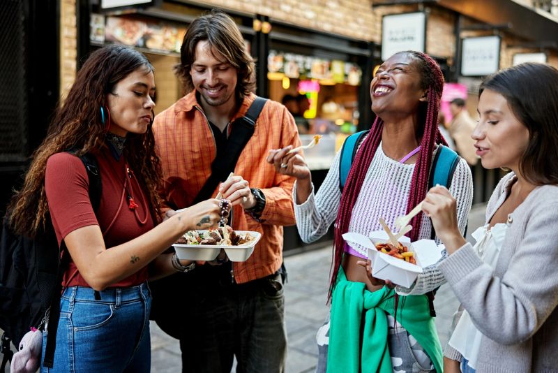 Londoners in 20s and 30s standing together, smiling and laughing, enjoying weekend leisure and afternoon treat.