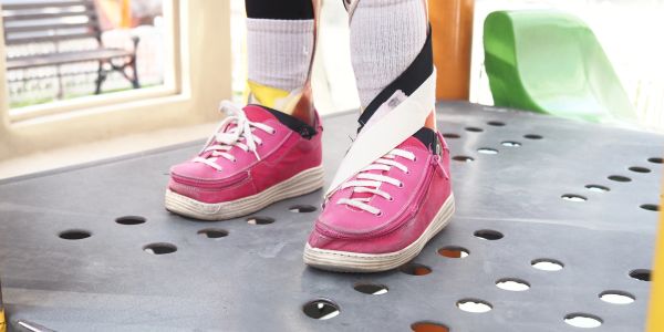 Person in pink shoes on a balance platform with ankle support straps.