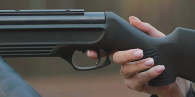 Person holding a black shotgun.